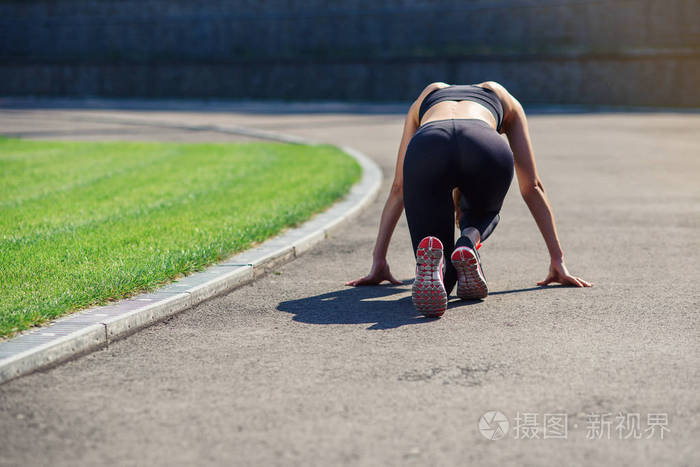 女运动员在体育场跑道的起跑线上准备跑后景.
