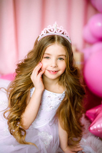 公主头冠一个金发碧眼的女孩穿着公主的淡粉色裙子,头冠上戴着气球