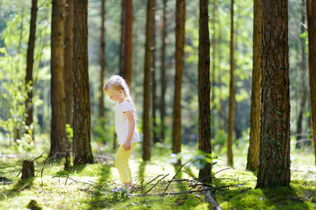 可爱的小女孩在美丽的夏日森林徒步旅行中玩得很开心。积极的家庭休闲与孩子。