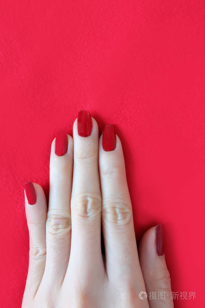 美丽的女人红指甲女性手与红色指甲修剪隔离在红色织物背景伟大的任何
