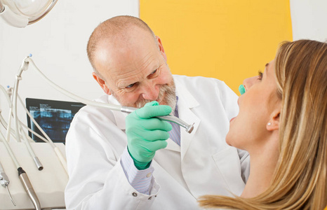 牙科医生用牙钻治疗女性病人