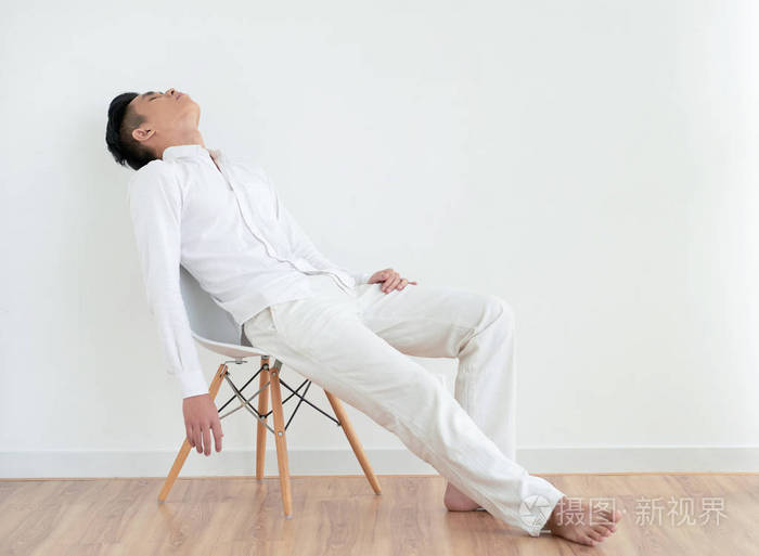 穿着简单的白色衣服睡在椅子上的年轻亚洲人