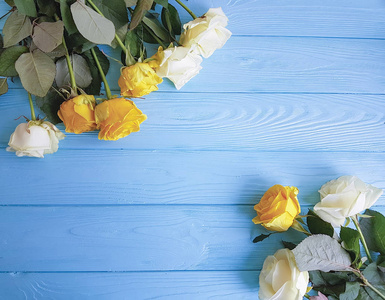 白色和黄色玫瑰在蓝色木制背景的地方供文字使用
