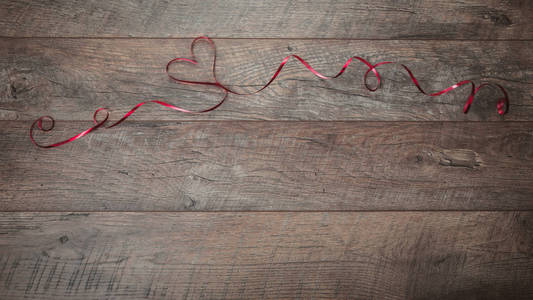 红丝带在一张深色的木桌上排列在形状的心脏上。情人节背景, 质朴的风格。情人节餐桌地方设置与红玫瑰和丝带。平躺, 顶部视图