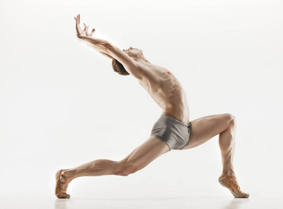 在完美的形状，在灰色的背景下执行运动的芭蕾舞演员