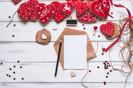 节日构图与手工制作的红色釉面饼干信纸片和铅笔在木制木板背景为情人节。