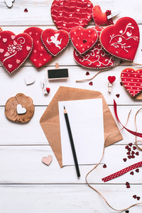 装饰构图与手工制作的红色釉面饼干信纸片和铅笔在木制木板背景上专用于情人节。