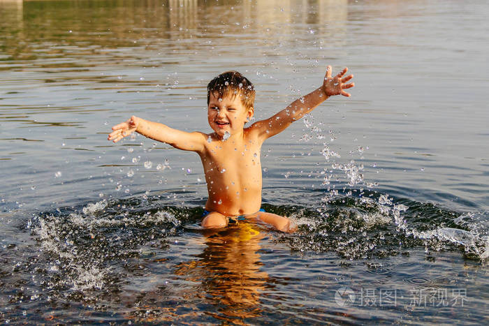 小男孩溅水阳光明媚的夏日在温暖的湖水中游泳