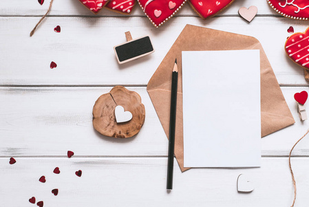 节日构图与手工制作的红色釉面饼干信纸片和铅笔在木制木板背景为情人节。
