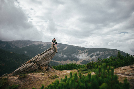 男人坐在岩石上，有着风景的背景