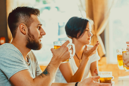 朋友们在酒吧里喝着一杯淡啤酒。 啤酒节的美丽背景。 一群年轻人在酒吧放松。 好的谷物。 柔和的焦点。 浅沟