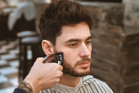 年轻的理发师向有吸引力的男人，在理发店理发的手