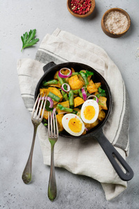 在灰色混凝土背景下，在煎锅中加入青豆胡椒欧芹鸡蛋和红葱的温土豆沙拉。 选择性聚焦。 上面的风景。 复制空间。