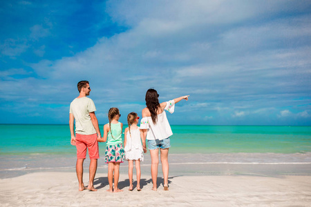 海滩上幸福美满的家庭。加勒比父母和孩子的背观