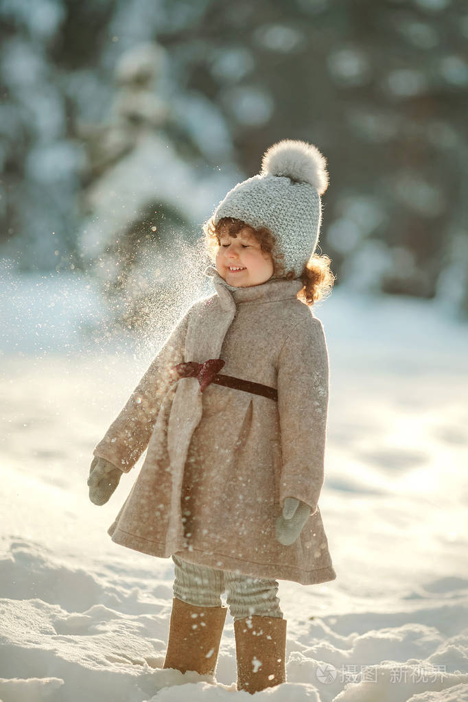 可爱的小女孩站在雪地森林里的老式外套手套和毡靴