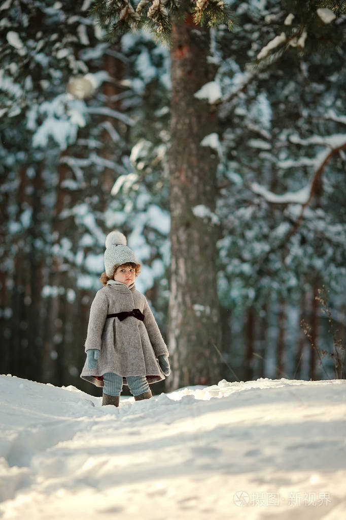 可爱的小女孩站在雪地森林里的老式外套手套和毡靴照片-正版商用图片