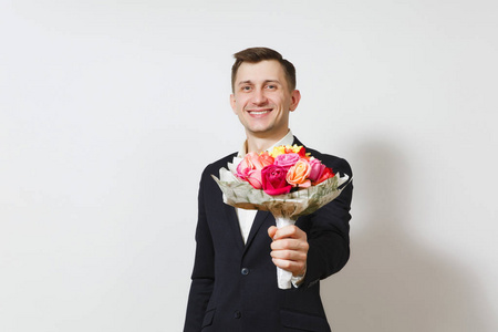 年轻英俊的笑容迷人的男人穿着西装, 衬衫捧着花束的美丽玫瑰花在白色背景上隔绝。St. 情人节, 国际妇女节, 生日, 节日概念