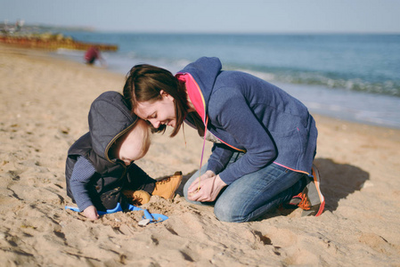 海亲子年轻女子玩海沙滩背景与小可爱的孩子, 好心情.