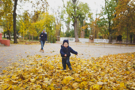 年轻女子走在秋天公园与小可爱的孩子男婴, 赶上, 运行在干燥的黄色秋叶。妈妈, 小孩子儿休息。亲子, 家庭日 5月15日, 爱
