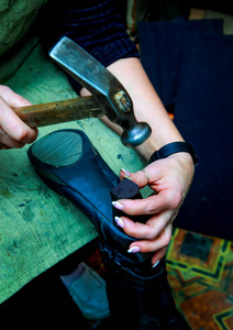 鞋匠拿着一只鞋和一把锤子, 钉住了脚跟。