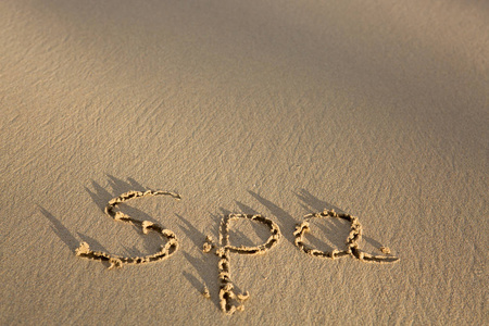 文字水疗写在海边的沙滩上。度假理念
