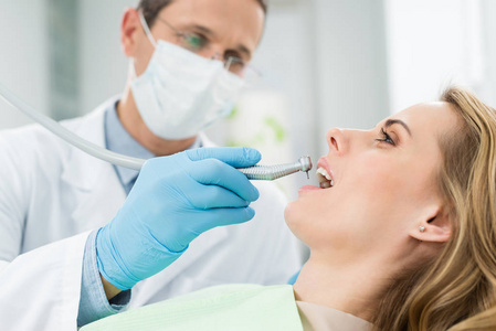 现代牙科诊所使用牙科钻进行牙科手术的女性病人