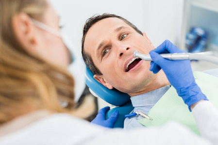 现代牙科诊所使用牙钻进行牙科手术的男性病人