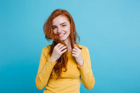 微笑着看着相机的雀斑的快乐姜红头发女孩的画像。淡蓝色背景。复制空间