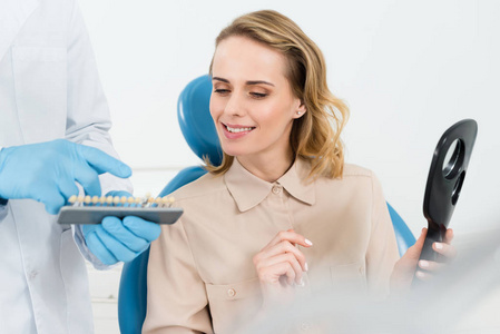 向现代牙科诊所的女性病人展示种植牙的医生