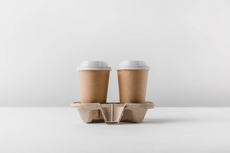 两杯纸杯咖啡放在桌上的纸板托盘里