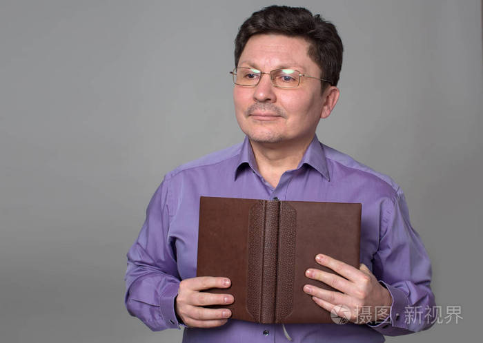 中年男人戴着眼镜手里拿着一本书