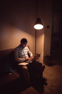 年轻人夜间使用笔记本电脑的肖像。 商人在办公室工作到深夜。 垂直射击。