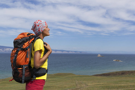 年轻的旅游女孩背着背包在贝加尔湖上散步，徒步远足西伯利亚