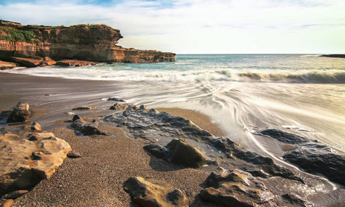 在新西兰南岛的煎饼岩石上长时间暴露在岩石海滩上的波浪