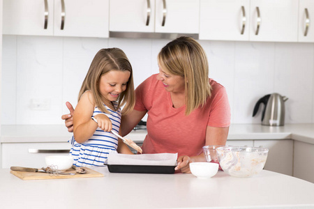 年轻的母亲和甜美的小女儿一起烘烤在家庭生活中快乐家居厨房的概念