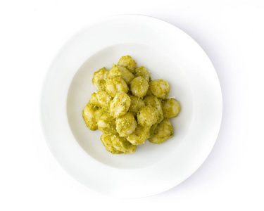 在白色背景上分离的盘子中含有Pesto酱的Gnocchi。 顶部视图