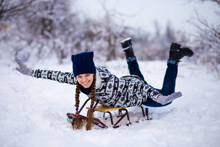 疯女人喜欢坐雪橇。 女人雪橇。 有趣的女人在雪地里户外玩耍。 冬天，女人在阿尔卑斯山的山上雪橇。 圣诞节假期的户外乐趣。