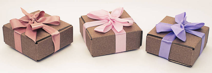 横幅三个节日盒子与礼物绑在缎带上的白色背景。 俯视图平躺