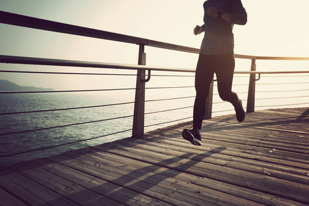 运动的女跑步者日出时在海滨木板路上跑步照片