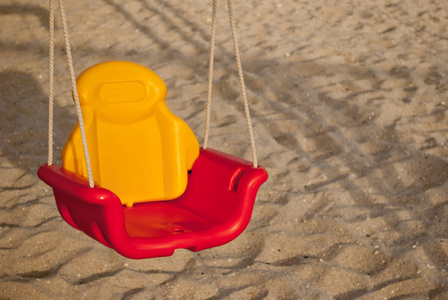 s bright swing of plastic on a rope, on the background of sand, 