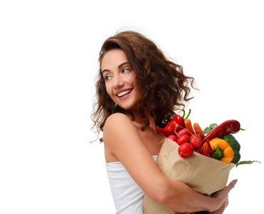 年轻女子拿着杂货纸购物袋里满是新鲜的蔬菜。饮食健康饮食观