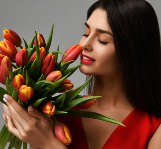 美丽的女人与花束的郁金香花在红色礼服