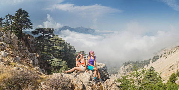 在岩石顶部的快乐女人, 看着夏天日落时的海边和雾山