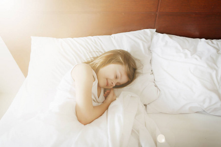 在白床上熟睡的小女孩的阳光画像
