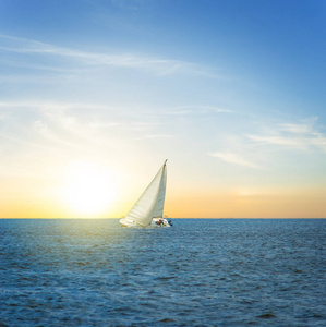 日落时分,一艘白色的帆船在大海中航行照片