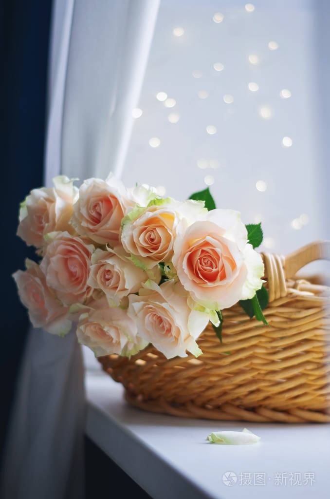 窗台上编织的篮子里的淡粉色奶油玫瑰花束.具有复制空间的浪漫背景