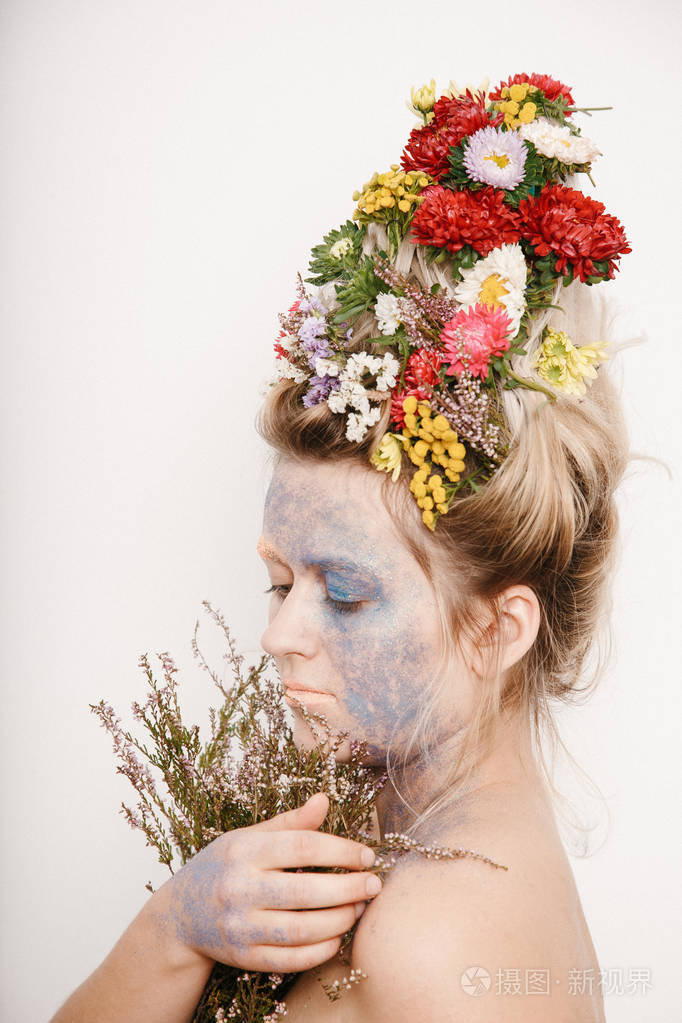 有五颜六色植物的人.女孩和盛开的理发和织锦在她的脸上