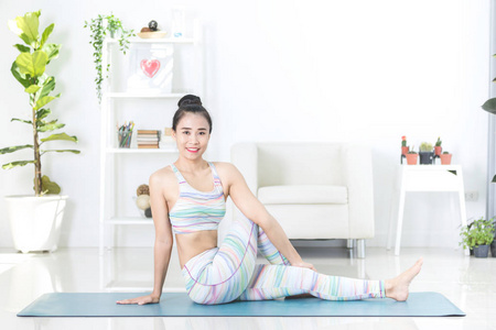 美丽的亚洲运动女性在家里做练习。瑜伽