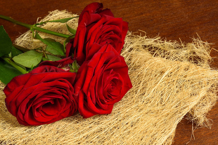 束美丽的红玫瑰，在黑暗的木制背景特写
