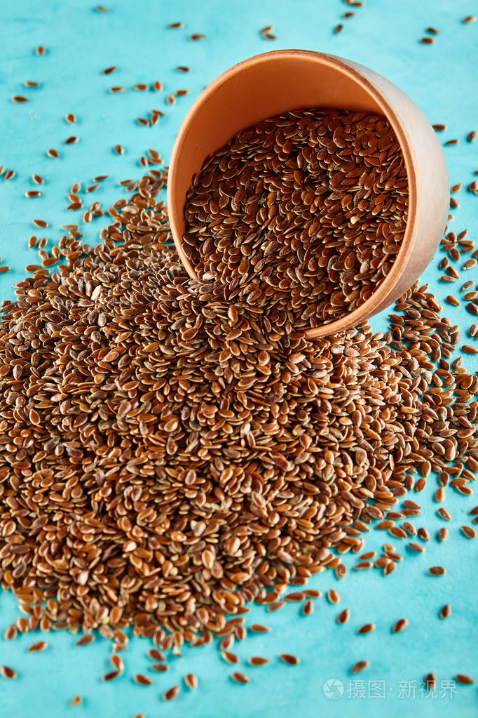 亚麻籽在黏土碗被隔绝在蓝色背景特写选择性焦点垂直